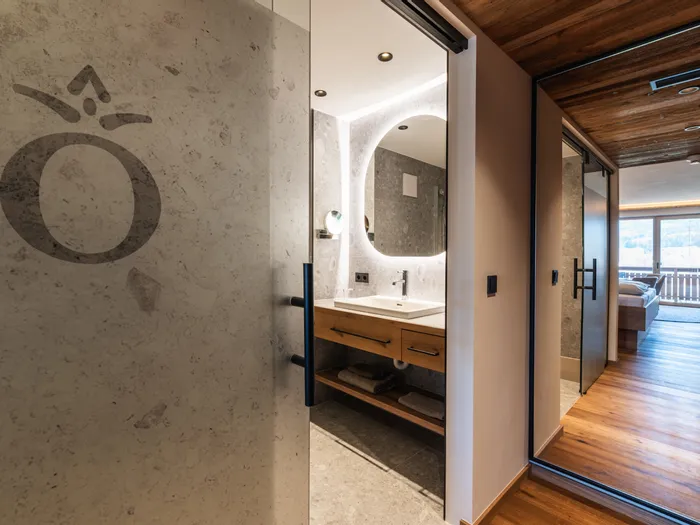 Modernes Hotelzimmer mit beleuchtetem Badezimmerspiegel und Holzboden bis zum Balkon